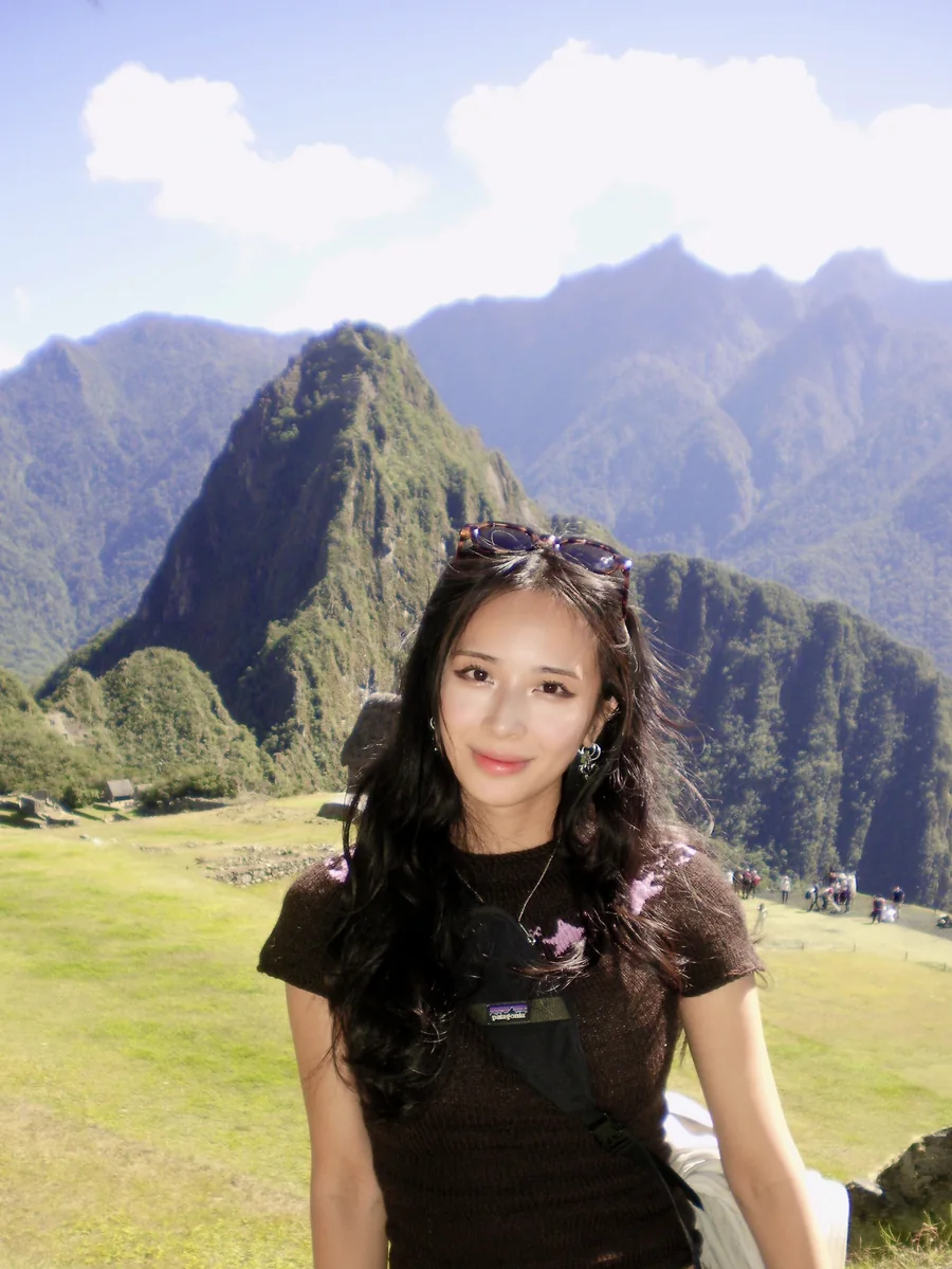 Jasmine smiling in front of green mountain peaks under a blue sky